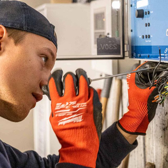 Ansatt skrur på et elektrisk anlegg